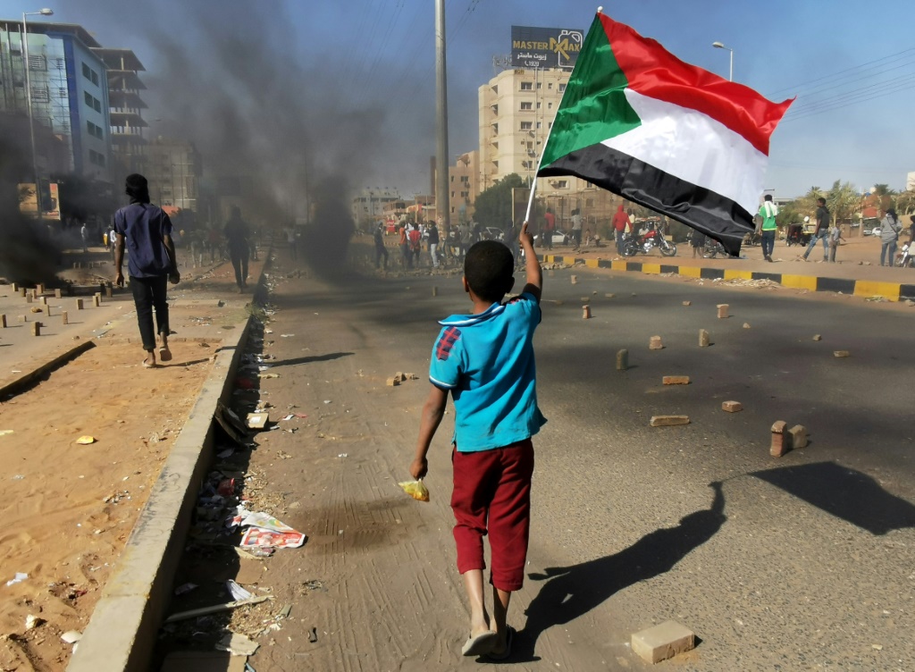 A Young Boy Waves A Sudanese National Flag As Protesters Block A Street In The Capital Khartoum, During A Demonstration Against The Killing Of Dozens In A Crackdown Since Last Year'S Military Coup, On January 20, 2022 | Afp