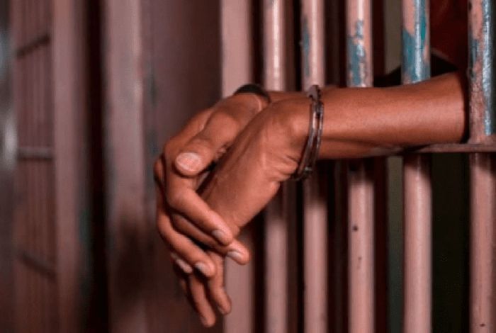 A Photo Of Person'S Hands Resting On Jail Bars At A Police Station.